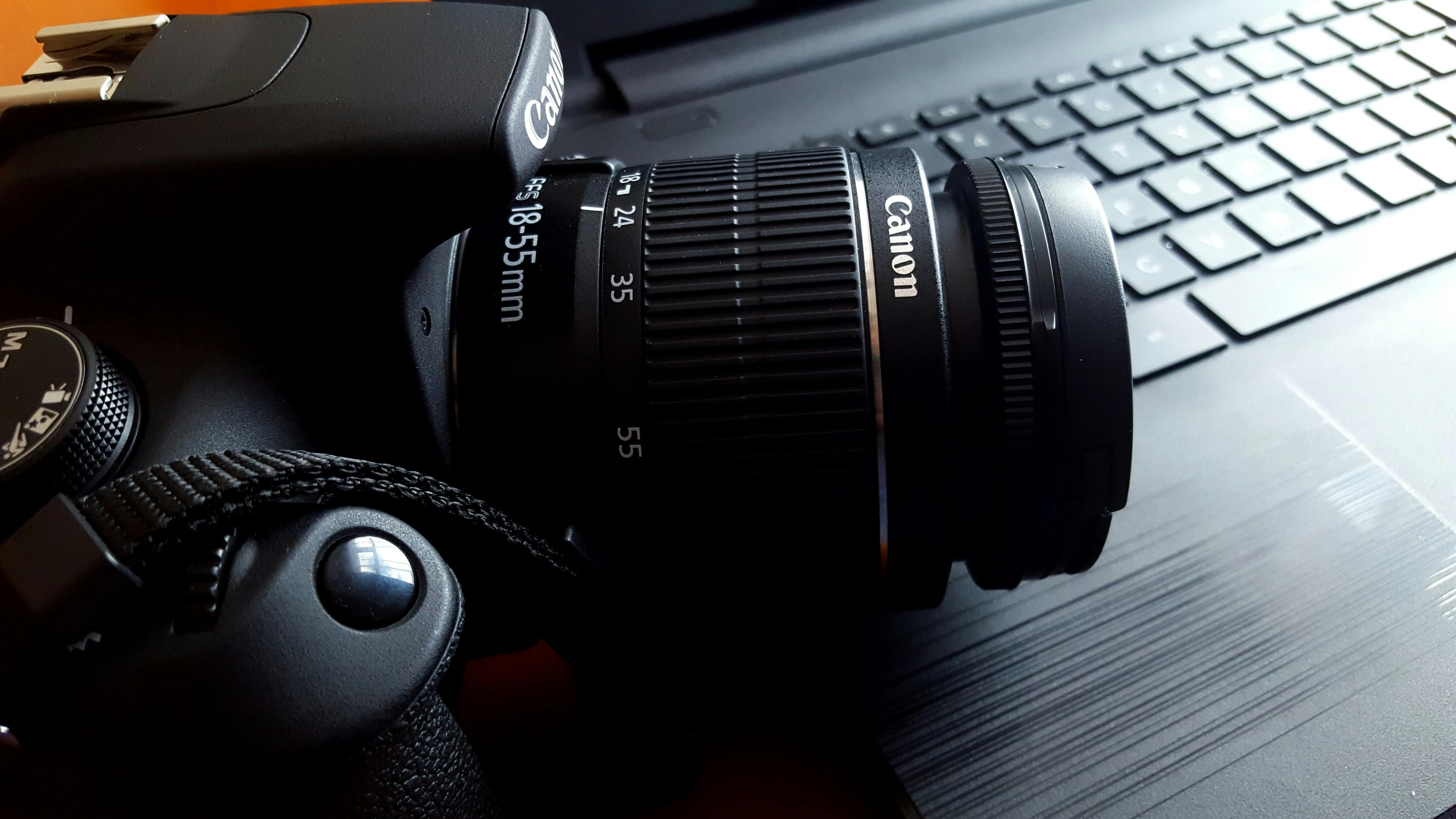 a canon cameria on top of a black laptop keyboard